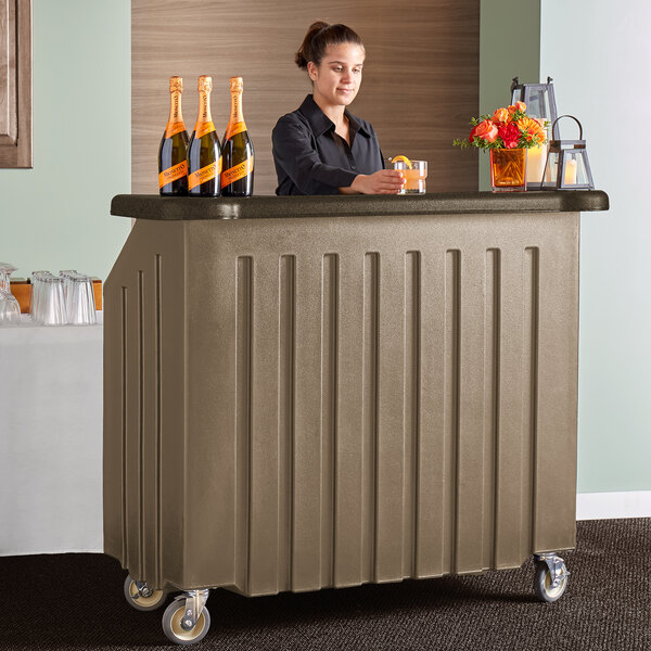A woman in a black shirt standing behind a Cambro Designer Series Portable Bar with drinks.