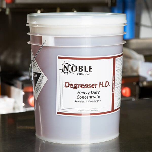 A Noble Chemical 5 gallon bucket of degreaser on a counter.