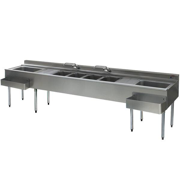 A large stainless steel Eagle Group underbar sink with four compartments, two drainboards, two faucets, and two ice bins.