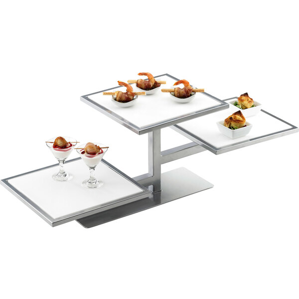 A Cal-Mil silver three tier riser frame with food on it.