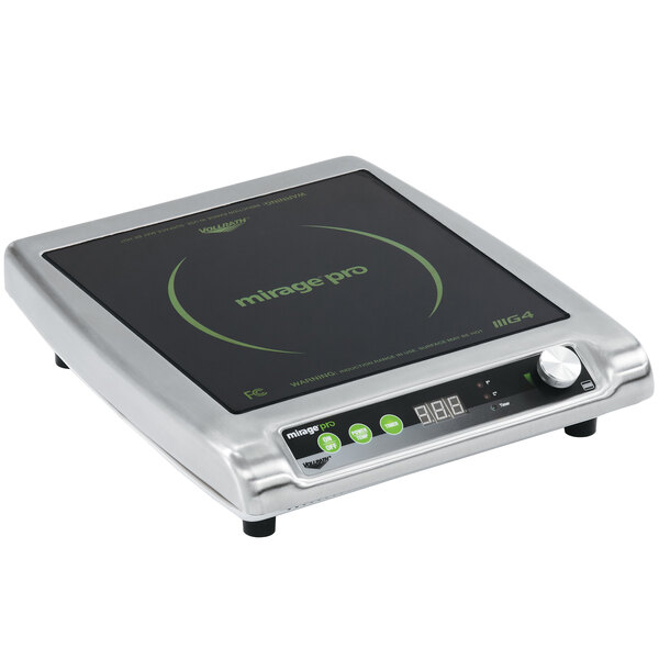 A Vollrath countertop induction range on a counter in a professional kitchen with green buttons.
