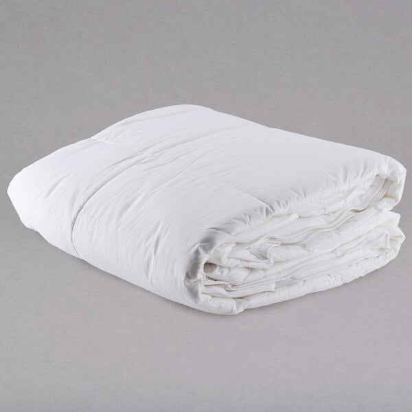 A white Oxford 100% cotton hotel duvet insert folded on a gray surface.