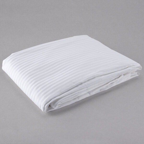An Oxford Super Blend white tone on tone striped duvet cover folded on a gray surface.