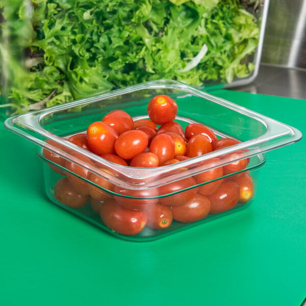 A Carlisle clear plastic food pan filled with cherry tomatoes on a counter.