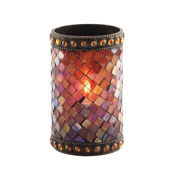 A Sterno amber beaded mosaic liquid candle holder with a lit candle on it.