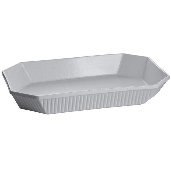 A natural cast aluminum octagon casserole dish with a lid on a white tray.