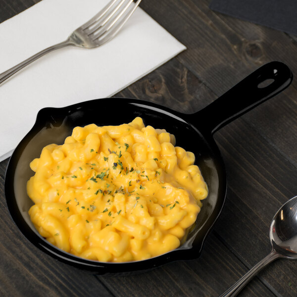 A Tablecraft black cast aluminum fry pan with macaroni and cheese on a table.