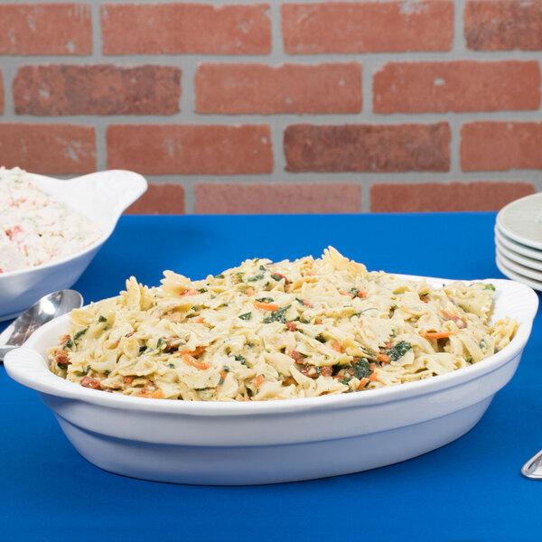 A white Tablecraft cast aluminum oval casserole dish filled with pasta and salad.