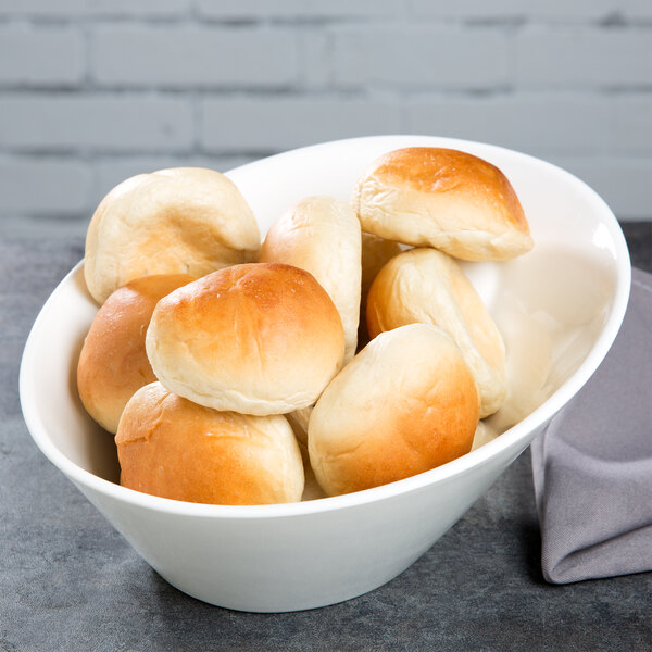 A white 10 Strawberry Street Whittier porcelain bowl filled with bread rolls.