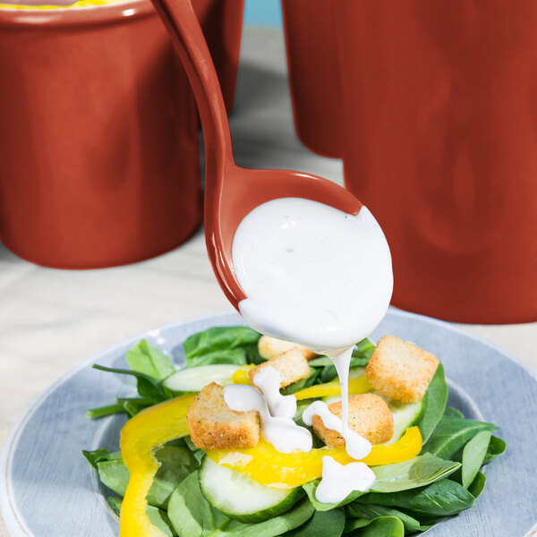 A Tablecraft copper ladle pouring dressing over a salad.