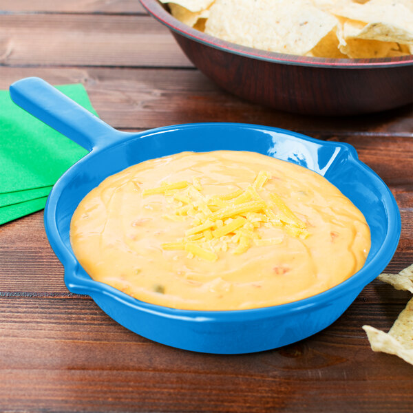 A Tablecraft sky blue cast aluminum fry pan filled with cheese dip next to a bowl of chips.