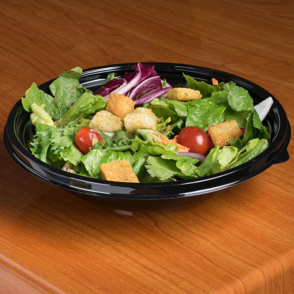A salad in a black bowl on a table.