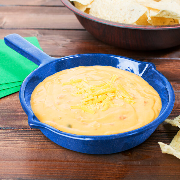 A Tablecraft blue speckle cast aluminum fry pan filled with cheese dip next to a bowl of tortilla chips.
