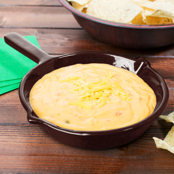 A Tablecraft midnight speckle fry pan with a bowl of cheese dip next to a bowl of chips.