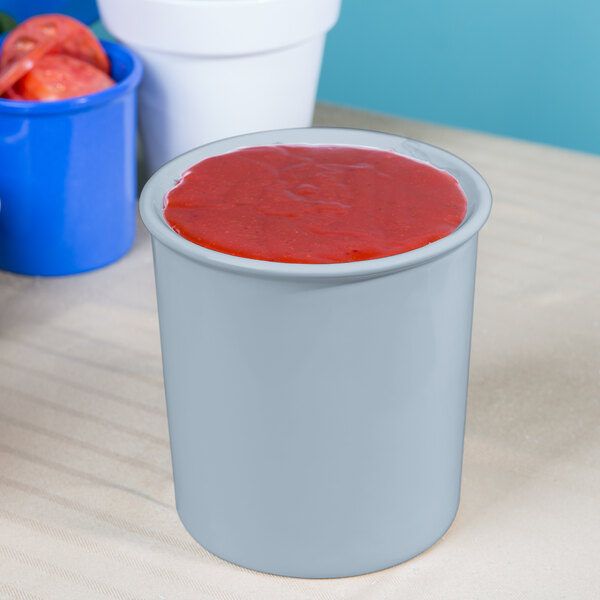A Tablecraft gray cast aluminum salad dressing bowl filled with red liquid.