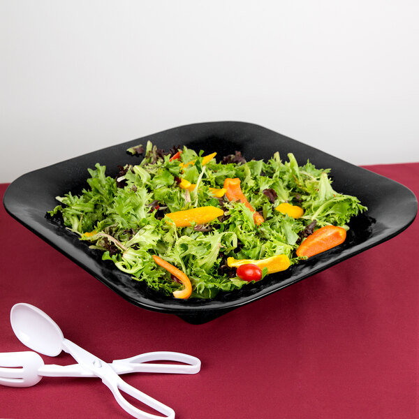 A salad in a black Tablecraft square bowl with a blue speckle.
