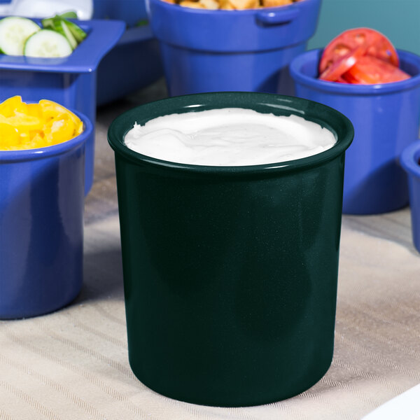 A hunter green container with white speckles containing salad dressing.