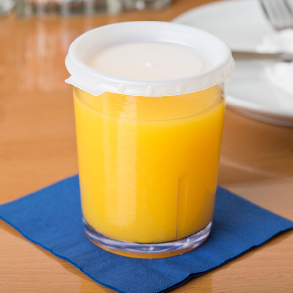 A Cambro translucent plastic lid on a plastic cup with yellow liquid in it.