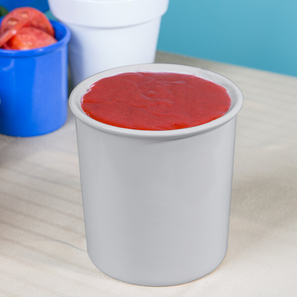 A white Tablecraft salad dressing bowl filled with red liquid.