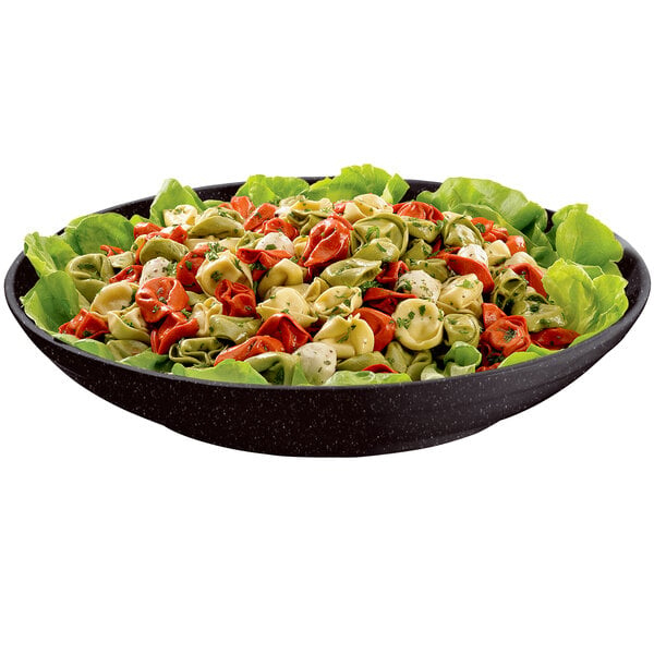 A Tablecraft midnight speckle pasta bowl filled with tortellini and lettuce on a table