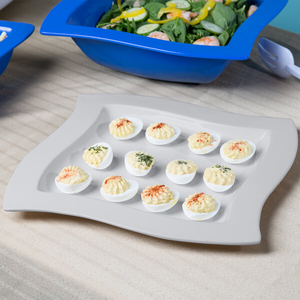 A Tablecraft natural cast aluminum square platter with deviled eggs and salad.