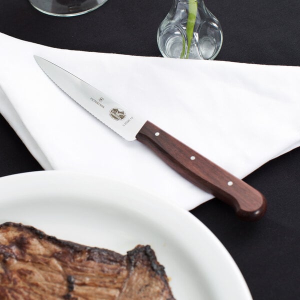 A Victorinox steak knife on a napkin next to a plate of steak.