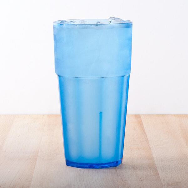 A blue plastic cup with ice on a wood surface.
