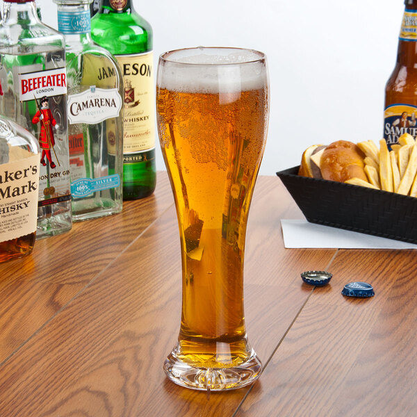 A Thunder Group plastic pilsner glass filled with beer on a table.