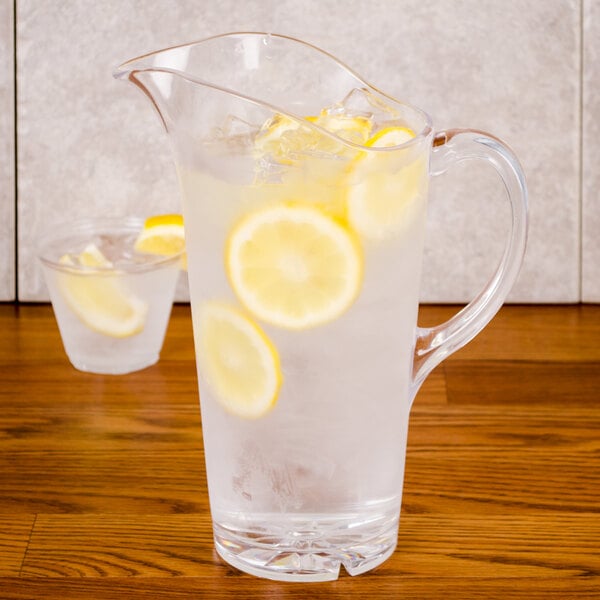 A Thunder Group polycarbonate water pitcher filled with water, lemon slices, and ice.
