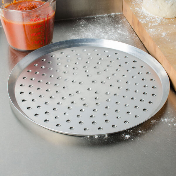 An American Metalcraft heavy weight aluminum pizza pan with perforations in the bottom.