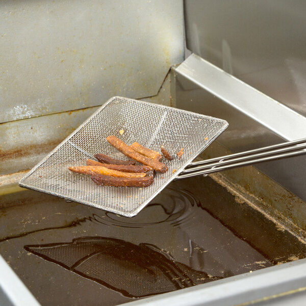 A 7" square fine mesh skimmer removing food from a fryer.