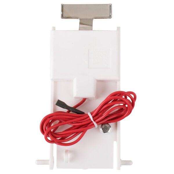 A white plastic device with a red wire.