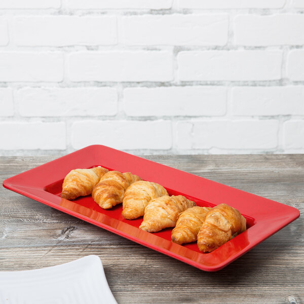 A red rectangular deep plate with croissants on it.