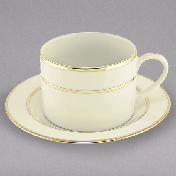A white porcelain can cup and saucer with gold trim.