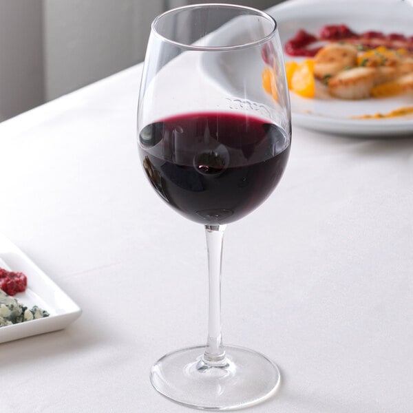 An Arcoroc Rutherford tall wine glass filled with red wine on a table.