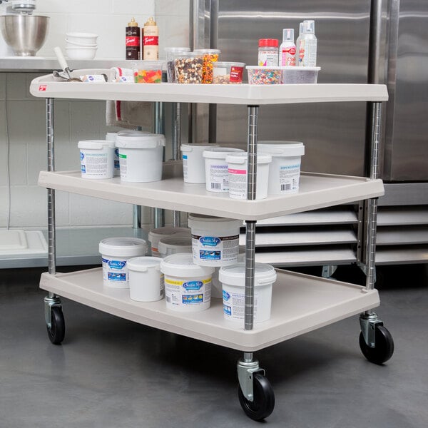 A Metro gray plastic utility cart with three shelves and chrome posts holding white containers.