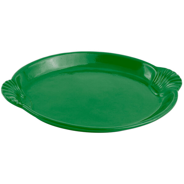 A green cast aluminum platter with a scalloped edge decorated with shells and fish.