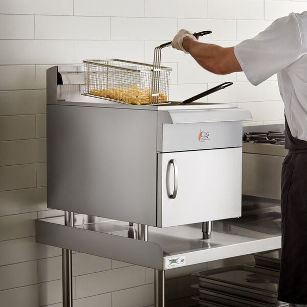 A chef using a Cooking Performance Group countertop gas fryer to cook french fries on a counter in a commercial kitchen.