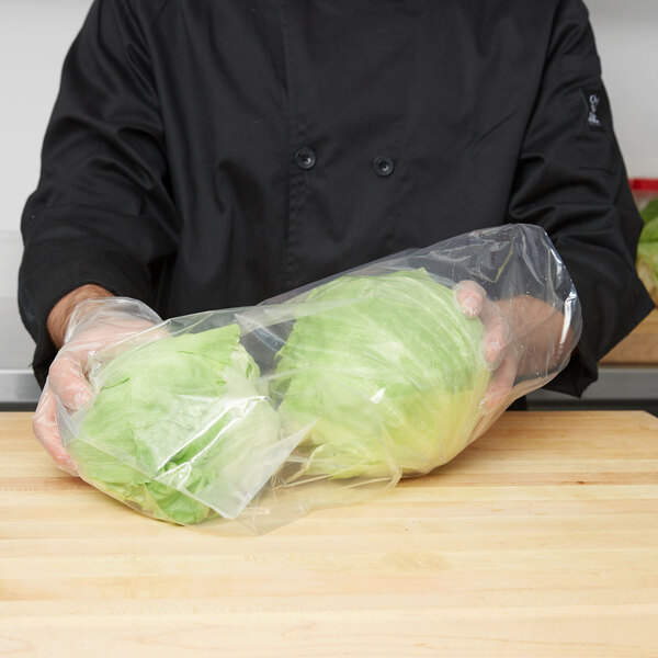 A person holding a plastic bag of lettuce.