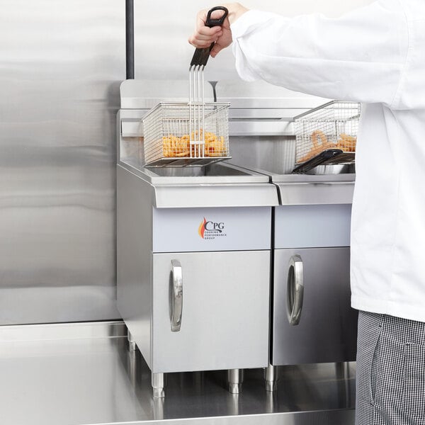 A chef in a white coat using a Cooking Performance Group natural gas countertop fryer to cook a basket of food.