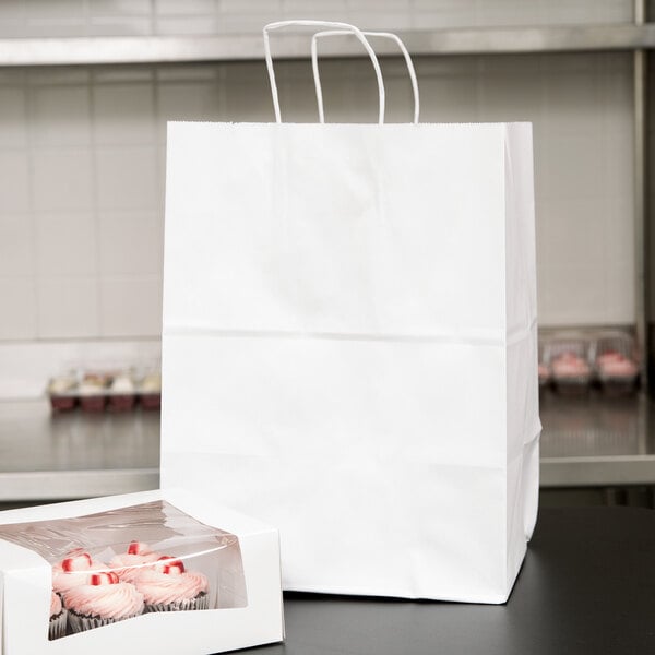 A white Duro paper shopping bag with cupcakes inside.