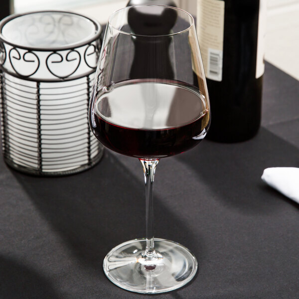 A close-up of a Spiegelau Bordeaux wine glass filled with red wine on a table.