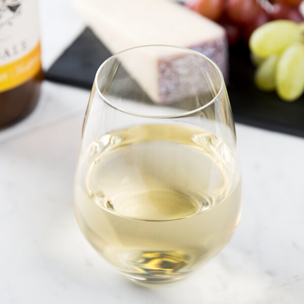 A Spiegelau Authentis stemless white wine glass filled with white wine on a table.