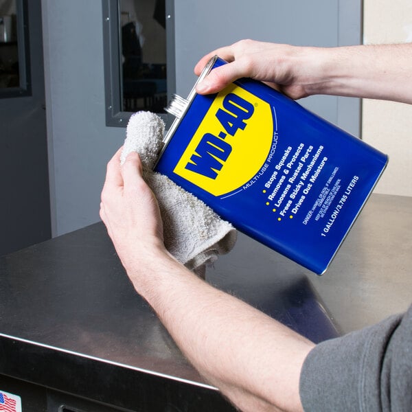 A person holding a gallon of WD-40 Heavy Duty Lubricant.