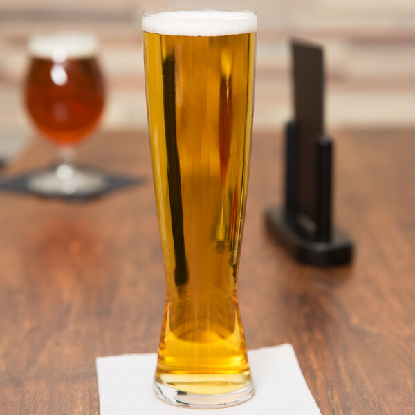 A Spiegelau tall Pilsner glass of beer on a table.