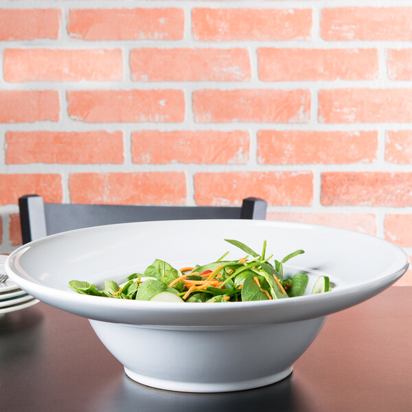 An American Metalcraft round stoneware bowl filled with salad on a table.