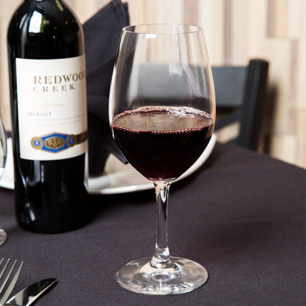A Spiegelau Bordeaux wine glass filled with red wine on a table.