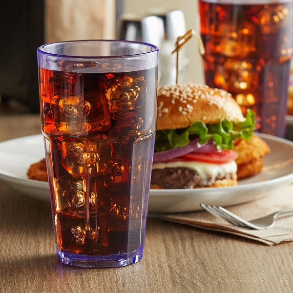 A blue GET Bahama plastic tumbler filled with cola and ice on a table next to a burger.