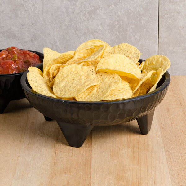 A black melamine molcajete bowl filled with chips and salsa.