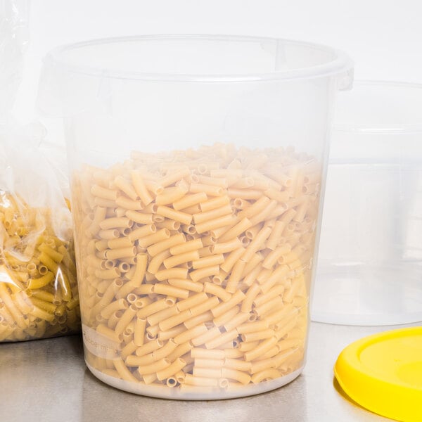 A Rubbermaid translucent plastic food storage container filled with pasta with a yellow lid.